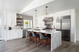 Fully furnished white color island kitchen with grey chairs in San Diego